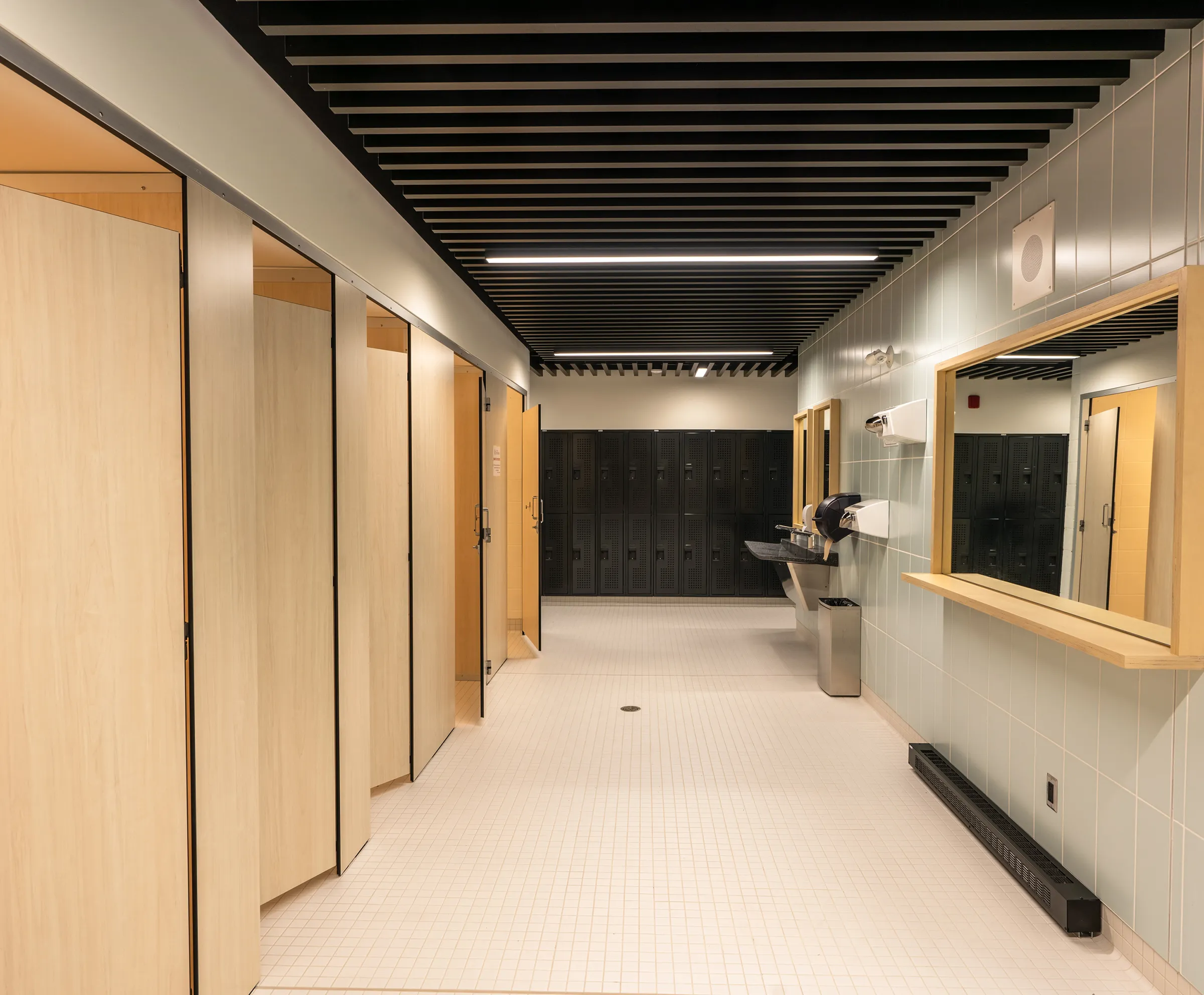 Vue intérieure d'un vestiaire avec casiers, cabines, lavabos et miroir