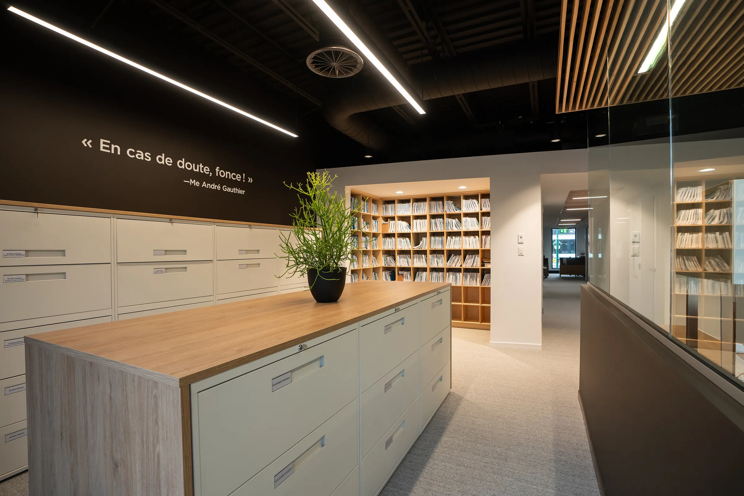 Vue intérieure d'une salle de document dans les bureaux de Cain Lamarre avec une citation au mur : « En cas de doute, fonce! » –Me André Gauthier